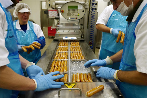 Employees packing Volkswagen currywurst sausages at German car manufacturing giant Volkswagen's sausage manufacturing plant ©AFP PHOTO/John MACDOUGALL