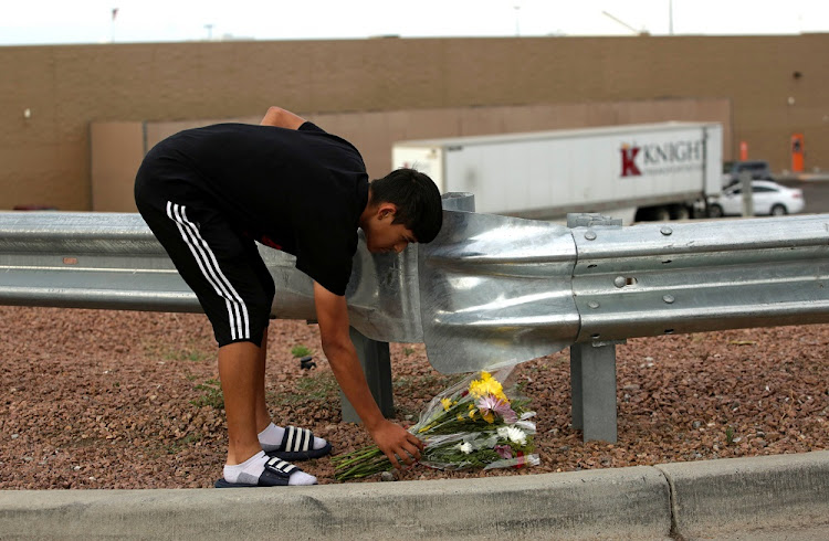 A man places flowers at the site of a mass shooting where 20 people lost their lives at a Walmart in El Paso, Texas, U.S. August 4, 2019.