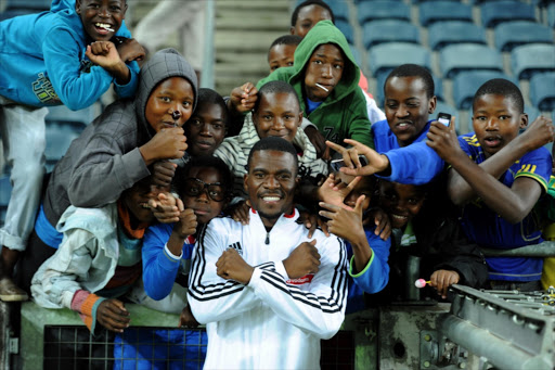 Senzo Meyiwa posing for a photograph with young pirates supporters during the Absa Premiership match between Orlando Pirates and Black Aces at Orlando Stadium on April 02, 2014 in Soweto, South Africa.