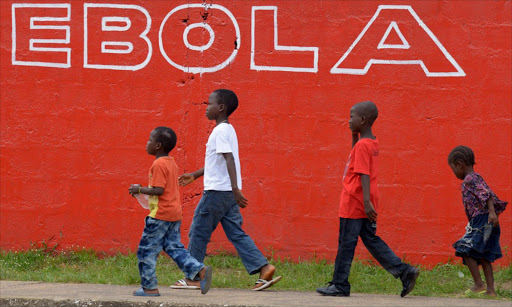 (FILES) This file photo taken on August 31, 2014 showing children walk past a slogan painted on a wall reading "Ebola" in Monrovia. The World Health Organization (WHO) announced on January 14, 2016 that the Ebola epidemic that has ravaged west Africa for two years was over after Liberia, the last affected country, received the all-clear.