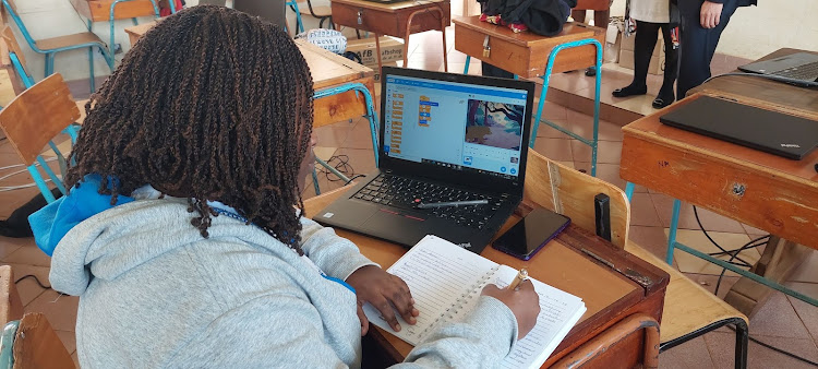 24-year-old law student, Maria Muneeni writing notes down after a coding class at Kenya High School