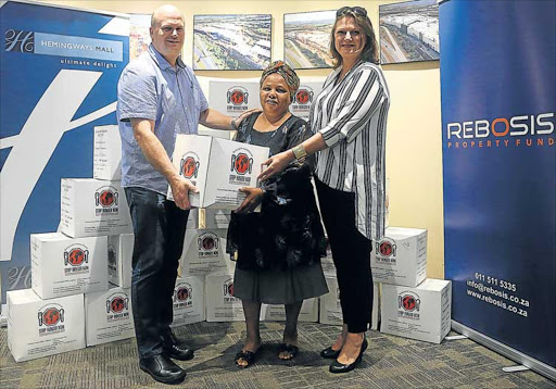 FOOD ON THE TABLE: Nomfuneko Salaze receives her meal boxes from Stop Hunger Now national operations manager Brian Nell and Hemingways Mall marketing manager Estee Roos Picture: SIBONGILE NGALWA