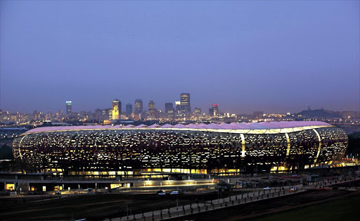 Soccer City Stadium, which hosted the main matches of the Fifa World Cup in 2010, lights up against the skyline of Johannesburg. Collusion by builders marred the tournament.