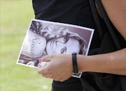 REST IN PEACE: A mourner departs, holding a picture of model  Reeva   Steenkamp , after her memorial service at the Victoria Park Crematorium in Port Elizabeth. Pic: Rogan Ward. 20/02/2013