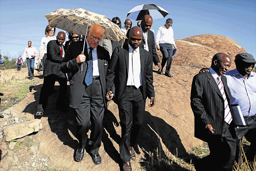Retired judge Ian Farlam, (with umbrella), visits the site of the Marikana massacre. He heads the commission of inquiry into the August 16 tragedy. File photo.