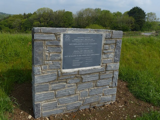 On an eastbound layby. The wording is in Welsh and English. The English states: This plaque was unveiled by EDWINA HART MBE CStJ AM Minister for Economy, Science and Transport on 16th April 2014...