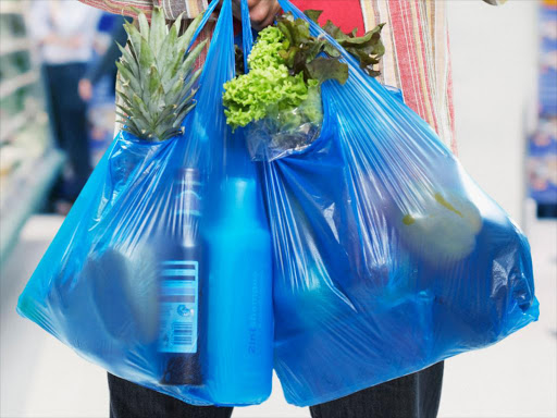 A shopper carrying goods in a plastic bag,./COURTESY