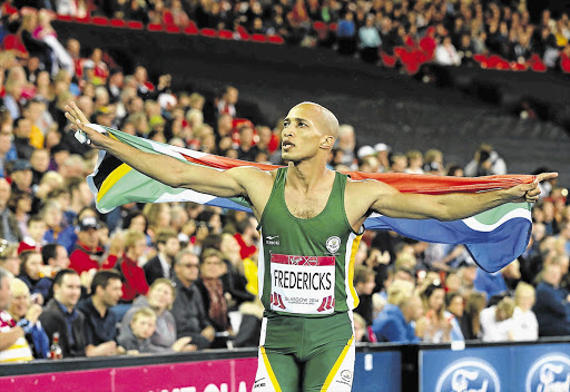 GO TEAM: SA's Cornel Fredericks celebrates his win in the 400m hurdles last night with a lap of honour at Hamden Park, the South African flag draped proudly around his shoulders