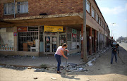 Locals clean up after over-night looting, when protesters took to the streets to demonstrate the killing of a boy in Coligny, North West province. REUTERS/Siphiwe Sibeko