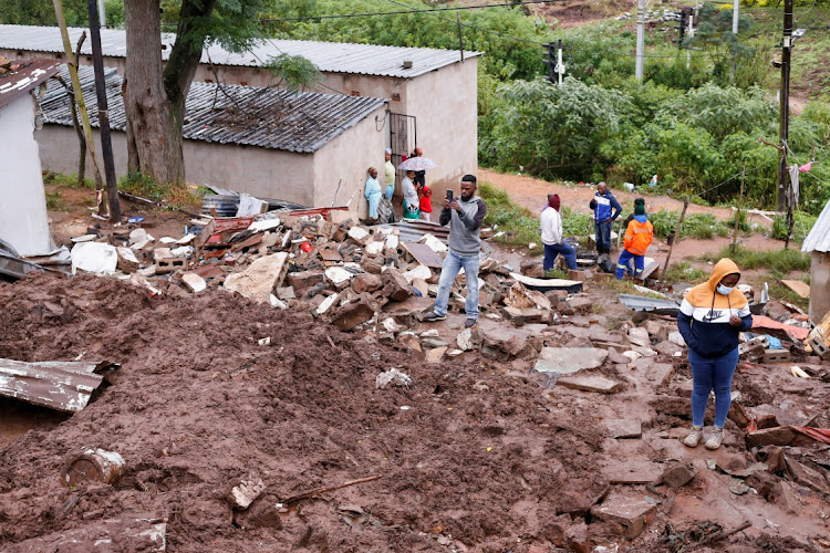 People stand amid the remains of a building destroyed by flooding at the KwaNdengezi Station, near Durban.