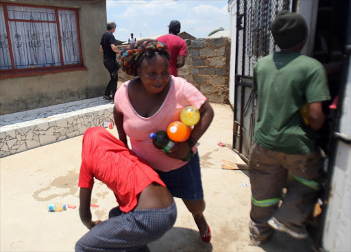 Residents carry goods which they took from a looted shop owned by foreign nationals on January 22, 2015 in Soweto. File photo.