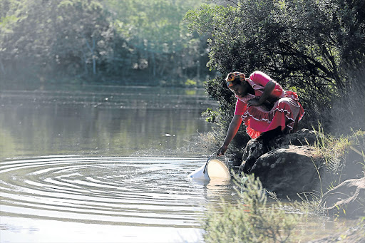 TIME-CONSUMING: Sisamkele Seyisi from Ezigodweni in Needs Camp collects water for washing. Residents in the area have sabotaged a pipeline, leaving thousands without water Picture: ALAN EASON