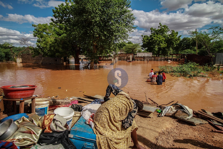 Women wade through water to salvage their belongings from Mororo village in Madogo after Tana River burst its banks on April 27,2024.