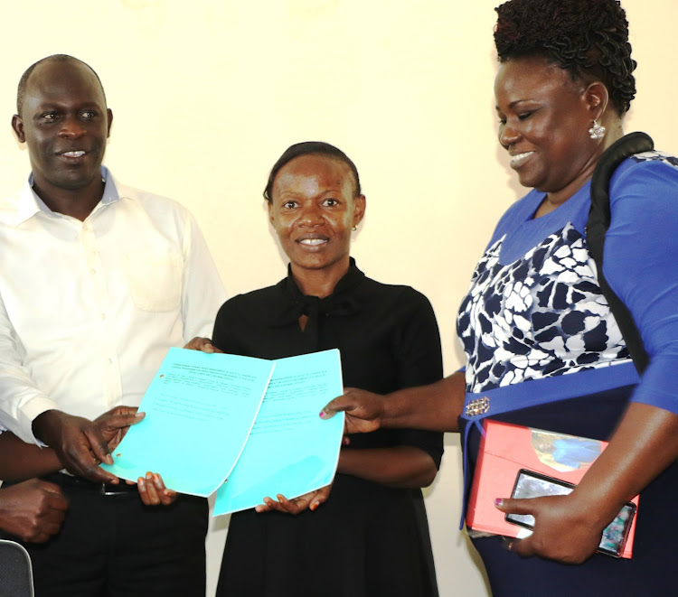 Busia director of medical services Janerose Ambuchi (R) and Busia County Referral Hospital deputy medical superintendent Emma Namulala receive copies on management of sickle cell from Prof Bernard Sorre of International Cancer Institute at the hospital on Wednesday January 22, 2020