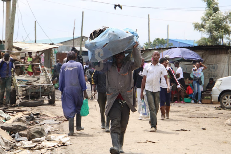 A man carries scrap metals after demolitions at Mukuru kwa Njenga on May 6, 2024.