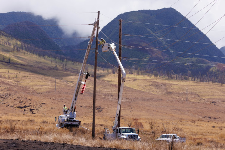 Electrical workers repair power lines leading into the fire ravaged town of Lahaina on the island of Maui in Hawaii, U.S., August 15, 2023. REUTERS/MIKE BLAKE/FILE PHOTO