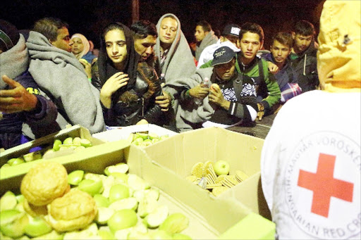 Crunch for refugees: Hungarian Red Cross provide food to migrants walking towards the Austrianborder at Hegyeshalom, Hungary, yesterday. Tens of thousands of migrants, most of them fleeing warand hardship in Syria, are trying to reach Western Europe.