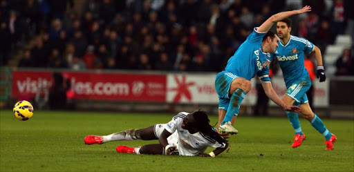 Swansea City's French striker Bafetimbi Gomis (L) is tackled by Sunderland`s Irish defender John O'Shea (R) during the English Premier League football match between Swansea City and Sunderland at The Liberty Stadium in Swansea, south Wales on February 7, 2015.