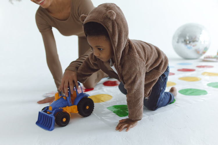 A mum helps a child play with a toy