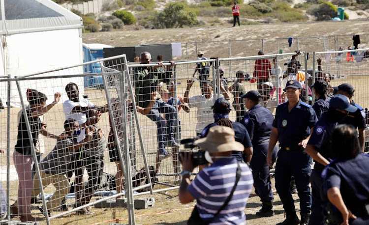 Residents at the Strandfontein lockdown camp for the homeless in Cape Town attempt to break a fence during a media visit on April 9 2020.