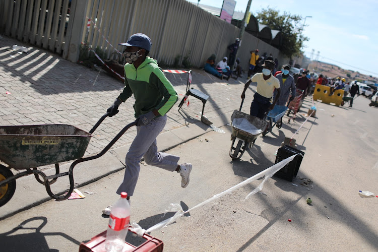 Residents offer their services to cart food parcels for a small fee on 2 May 2020 in Olievenhoutbosch in Centurion, north of Johannesburg. Residents came out in their thousands to receive food parcels.