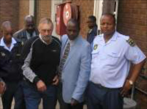 ARRESTED AGAIN: The accused in the alleged kidnapping of Ntsako Richard Mkhari, Johan van Niekerk, 69, accompanied by police to the Phalaborwa magistrate's court last Thursday. Pic. Alex Matlala. 26/07/07. © Sowetan.