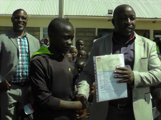 Let there be light: Laikipia East MP Anthony Mutahi presents a cheque to Benson Kamau, a former pupil of Bingwa Primary School, in Umande location on Friday as the head teacher Moses Kagema looks on.