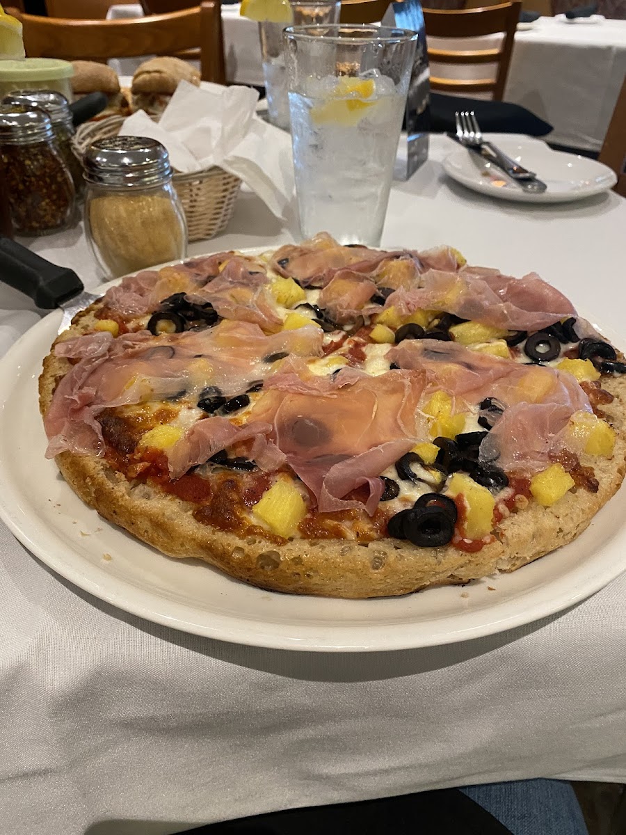 Gluten free pizza with pineapple, olive, prosciutto