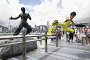 Chinese actor Mei Zhiyong delivers a flying kick in front of a bronze statue of kung fu legend Bruce Lee on the Hong Kong waterfront yesterday. Fans are gathering in the city for a series of events to mark the 40th anniversary of Lee's death