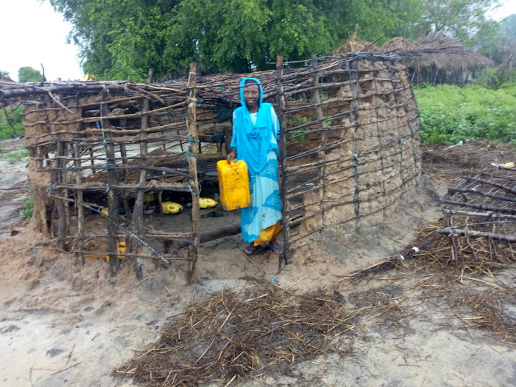 A woman stands next to her house which was destroyed by floods in Bodhei village, Lamu East