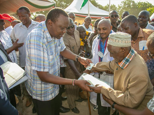 President Uhuru Kenyatta gives Mzee Hamisi Kinungi, born in 1935, an ID card during the issuance of the document to the Makondes in Msambweni on February 1 / PSCU