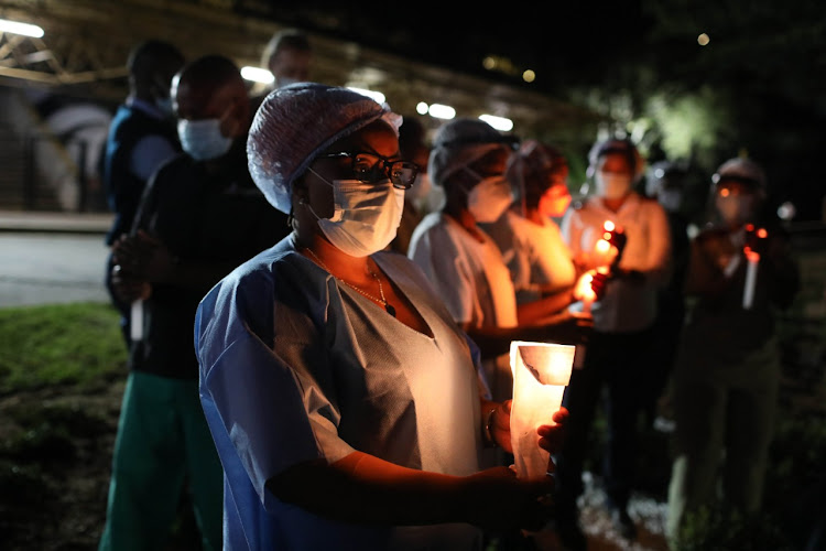 Health care workers light candles in the Heroes Garden at Charlotte Maxeke Hospital in Johannesburg to honour the frontline workers and those who have died due to the pandemic.