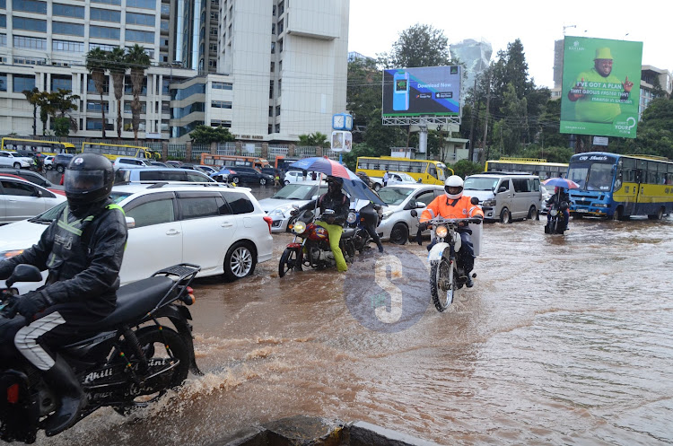 Nairobi residents brave the cold weather as they try to access their way home after a heavy downpour on April 24, 2024.