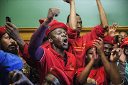 FILE PHOTO: Economic Freedom Fighters (EFF) members chant slogans after storming the Gauteng Legislature building after a march over a ruling against the wearing of red overalls in the Gauteng Legislature assembly. Photo credit: AFP