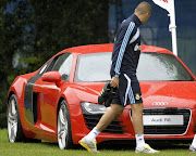 A file photo of Real Madrid's French striker Karim Benzema looks at a sport car after their first training session in Madrid.