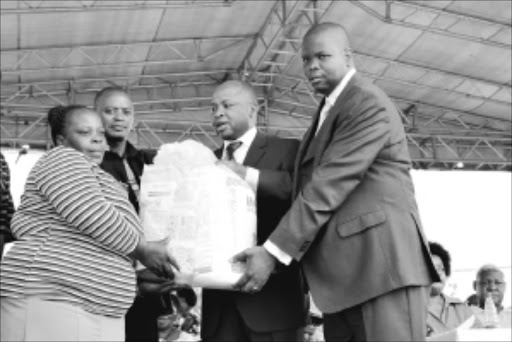 CELEBRATION: Premier Cassel Mathale, second from right, hands a food parcel to Vhangani Mudimeli. Venda paramount chief Toni Mphephu is on Mathale's left. Pic. Benson Ntlemo. 21/03/2010. © Sowetan.