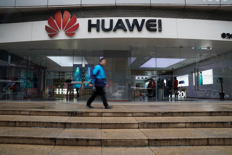 A man walks by a Huawei logo at a shopping mall in Shanghai, China.
