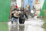 Neighbours help Thembakazi Vanqase, right, to salvage clothes from her flooded shack in an informal settlement near Kliptown, Soweto. Vanqase lost many of her possessions when the Klipspruit river burst its banks following heavy rain.