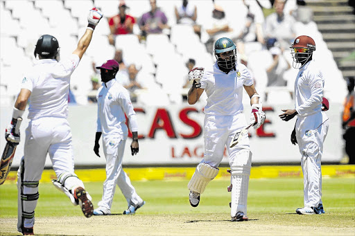 EASY IN: Dean Elgar, left, and Hashim Amla celebrate after hitting the winning runs in the third Test match between South Africa and the West Indies at Newlands cricket stadium in Cape Town yesterday. South Africa won the Test by eight wickets