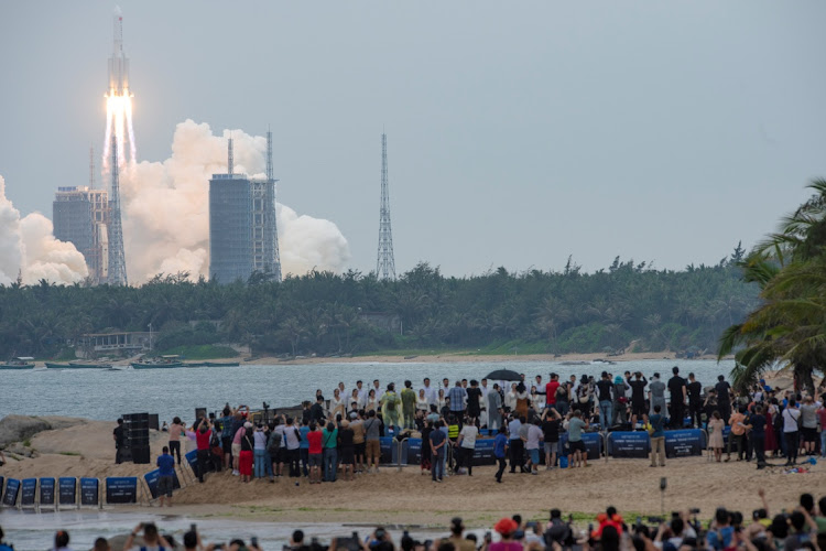 People watch from a beach as the Long March-5B Y2 rocket, carrying the core module of China's space station Tianhe, takes off from Wenchang Space Launch Center in Hainan province, China April 29, 2021.