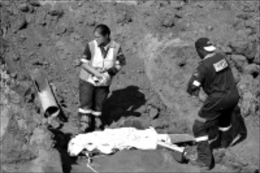 TOO LATE: Paramedics remove the body of Duncan Sebone, 3, who fell into a borehole at Dalmada outside Polokwane yesterday. 03/11/2008. Pic. Elijar Mushiana. © Sowetan.
