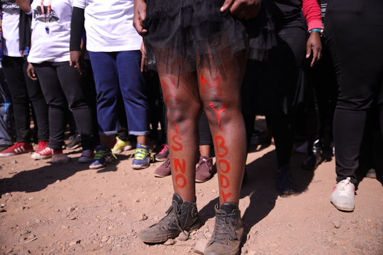 A woman shows slogans painted on her legs during the #TotalShutdown march in Pretoria on August 1, 2018.