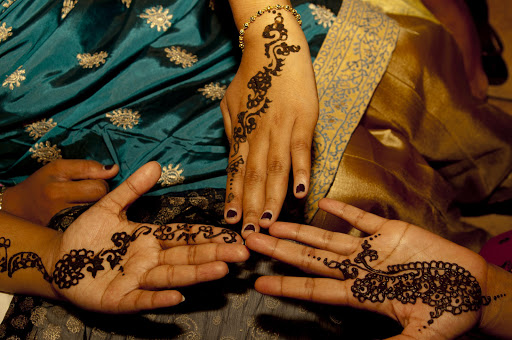 The women have their hands decorated with mehndhi (henna).