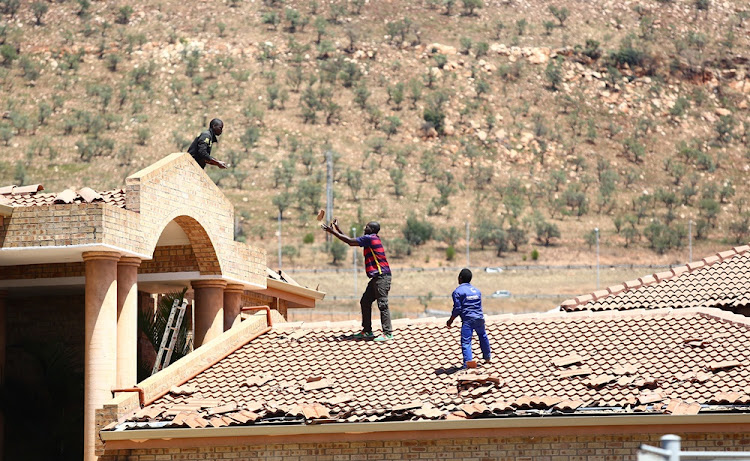 Construction workers fix a roof in Pinehaven Estate that was damaged during the stormy weather on 9 October 2017.