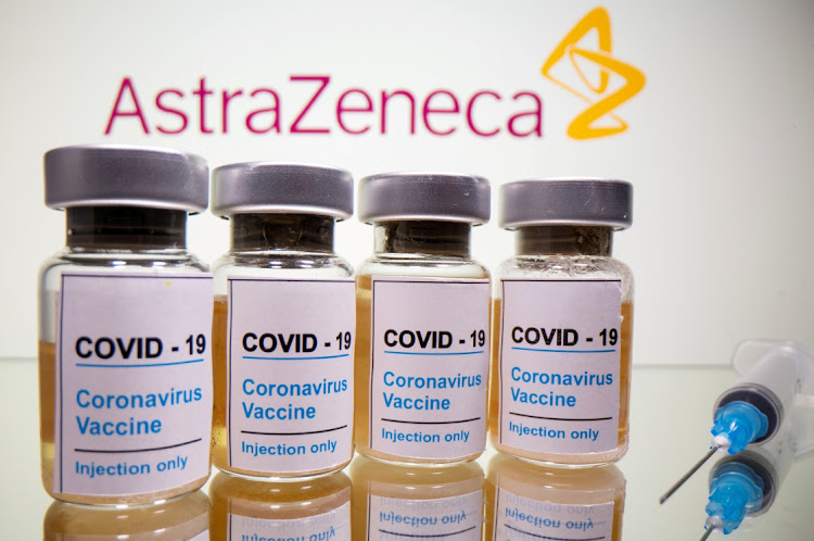 Vials with a sticker reading, "Covid-19 / Coronavirus vaccine / Injection only" and a medical syringe are seen in front of a displayed AstraZeneca logo in this illustration.