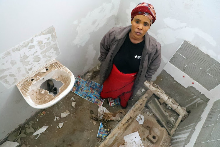 Nomawest Pitoli stands in the bathroom which was supposed to be hers but has been vandalised before she could move in, at the KwaMasiza Hostel in Sebokeng.