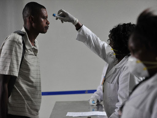 Health officials take passengers’ temperature on arrival at the Jomo Kenyatta International Airport, Nairobi, on August 14, 2014 /FILE