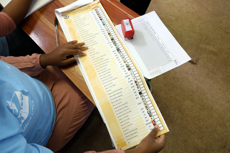 An IEC official studies a ballot paper at Hitekani Primary School in Chiawelo, Soweto.