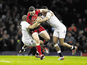 DAZED AND CONFUSED: George North of Wales is tackled by Jonathan Joseph and Anthony Watson of England during the match in which he was allowed to play on after losing consciousness