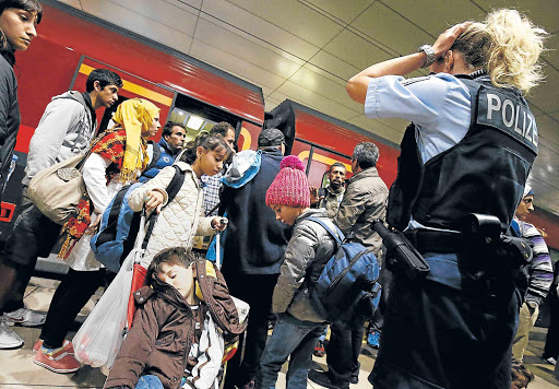 CROWD CONTROL: A German border police woman stands by as dozens of migrants unexpectedly disembarked from a train that left Budapest’s Keleti station for a station at the airport in Frankfurt, Germany, on Sunday. Austria and Germany threw open their borders to thousands of exhausted migrants on Saturday, bused to the Hungarian border by a right-wing government that had tried to stop them but was overwhelmed by the sheer numbers reaching Europe’s frontiers. The EU Commission is looking at further expanding quotas in terms of the number of refugees to be taken in by countries in the EU-bloc Picture: REUTERS